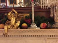 Faux fruit and holiday greenery on a mantel.
